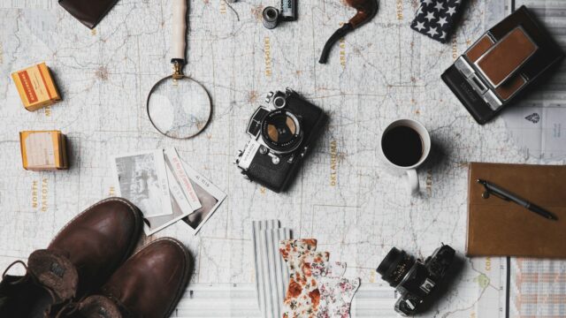 camera, pair of brown shoes, white ceramic mug, grey and black pen, brown smoking pipe